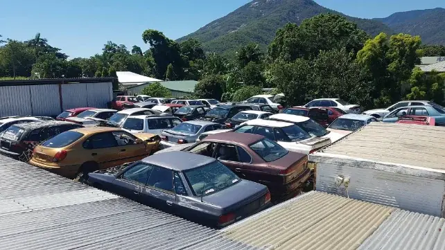 Wide view across rows of vehicles in the wrecking yard